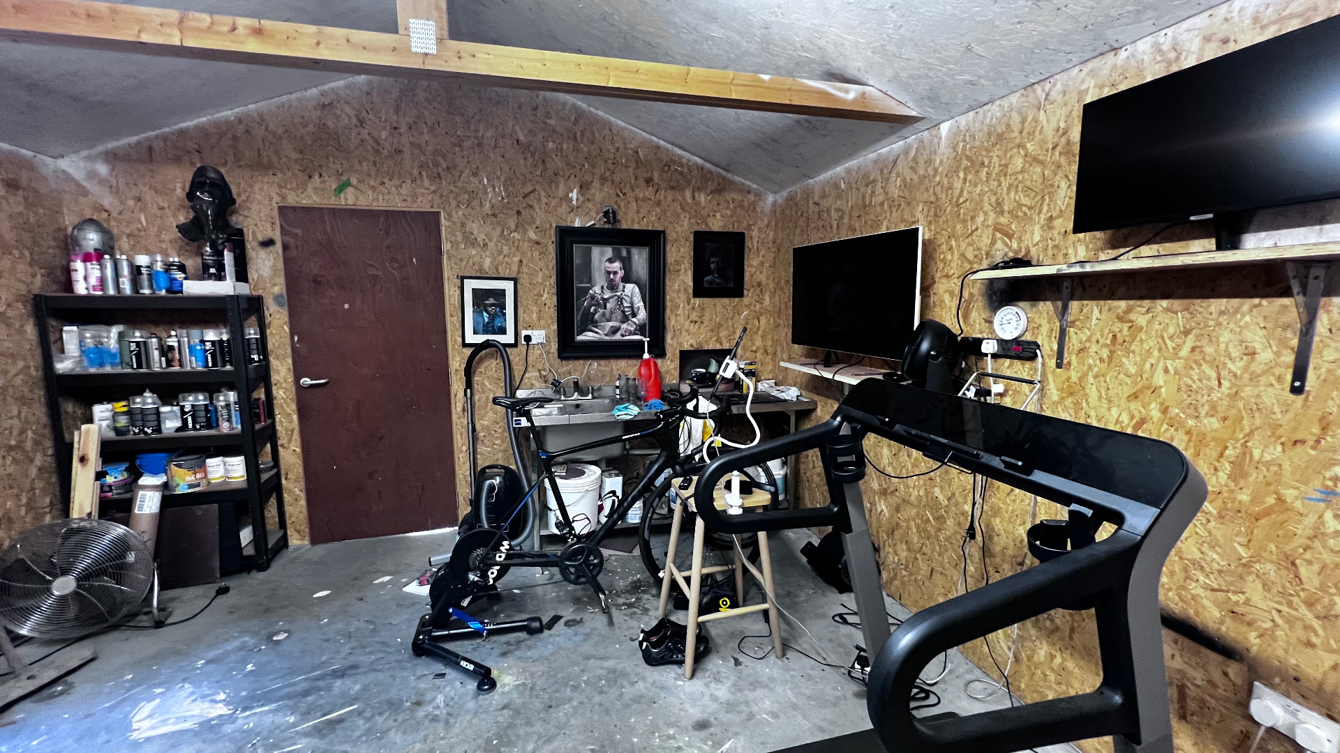 Before: the mixed-use working space with shelving, materials, screens and equipment all visible at once.